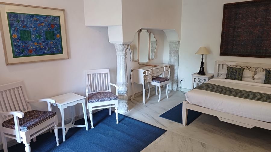 Guest room with white furniture, blue area rug, decorative pillows, vintage dresser, and contemporary art at Neemrana Fort-Palace - 15th Century, Delhi-Jaipur Highway.