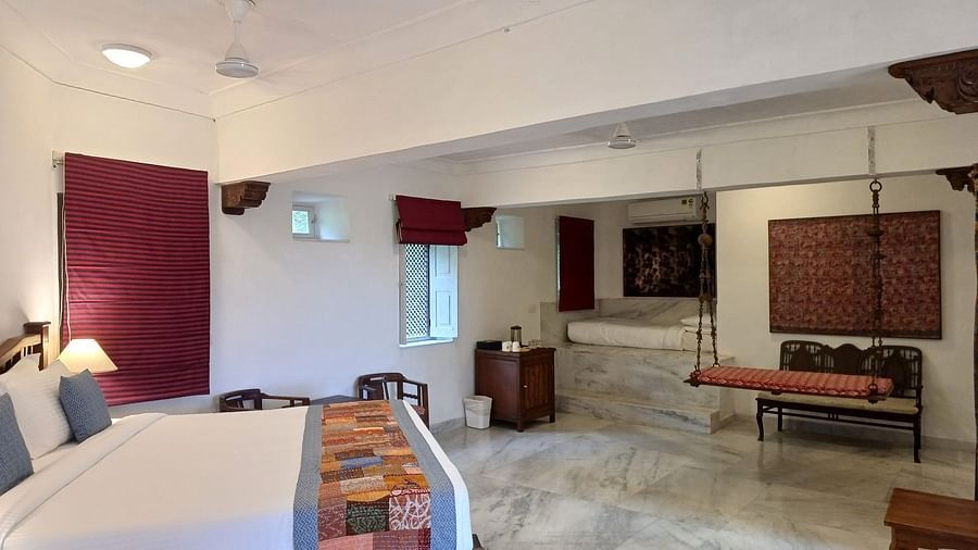 Spacious lounge area with period furniture and carved wooden chairs in the historic Neemrana Fort-Palace interior.