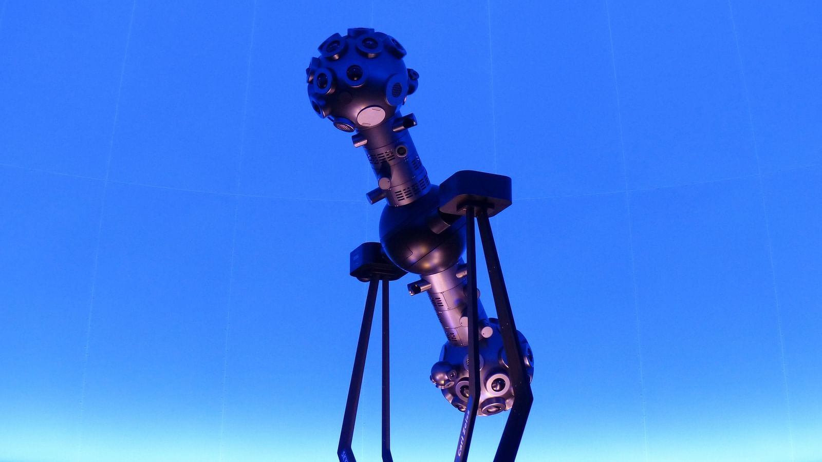 An overview of a star projector inside a planetarium with a blue screen in the background.