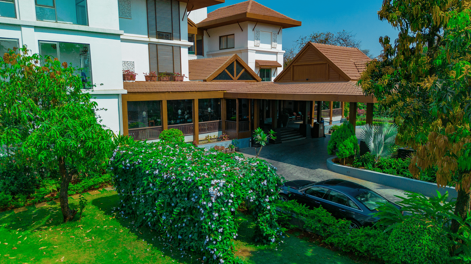 facade view of the Rhythm Lonavala: An All-Suite Resort with manicured garden and trees in view.
