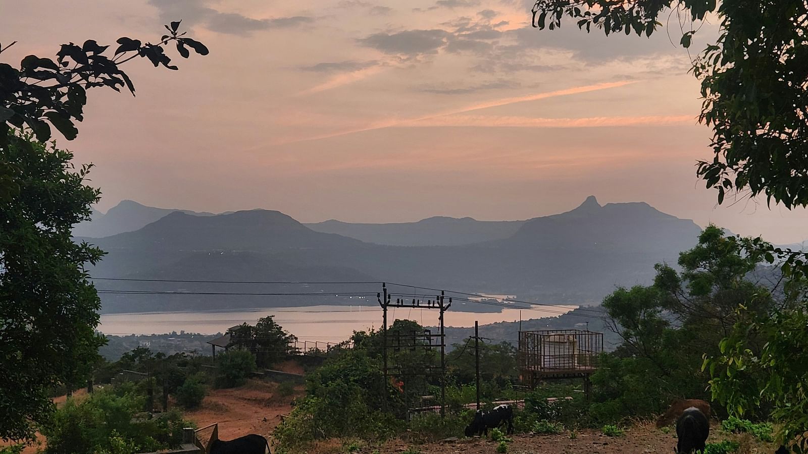 A view from afar of Pawna lake with mountains and different hues in the sky after sunset.