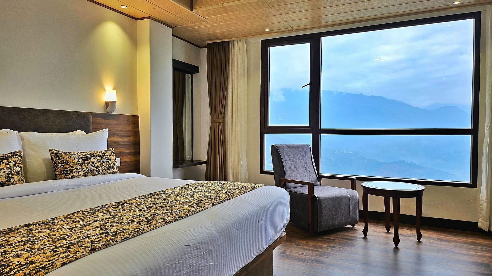 view of king size bed and chairs near the window of Premium Room at Sumitel Pelling, Geyzing