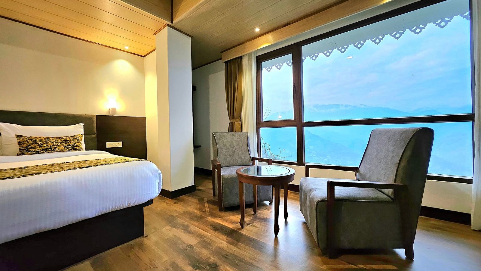 view of king size bed and chairs near the window of Premium Room at Sumitel Pelling, Geyzing