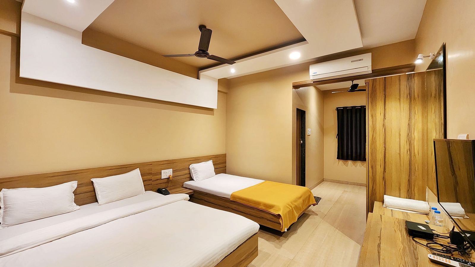 Triple Premium Room at The Kanila Resort featuring a bed with a gray headboard and white sheets and curtains.