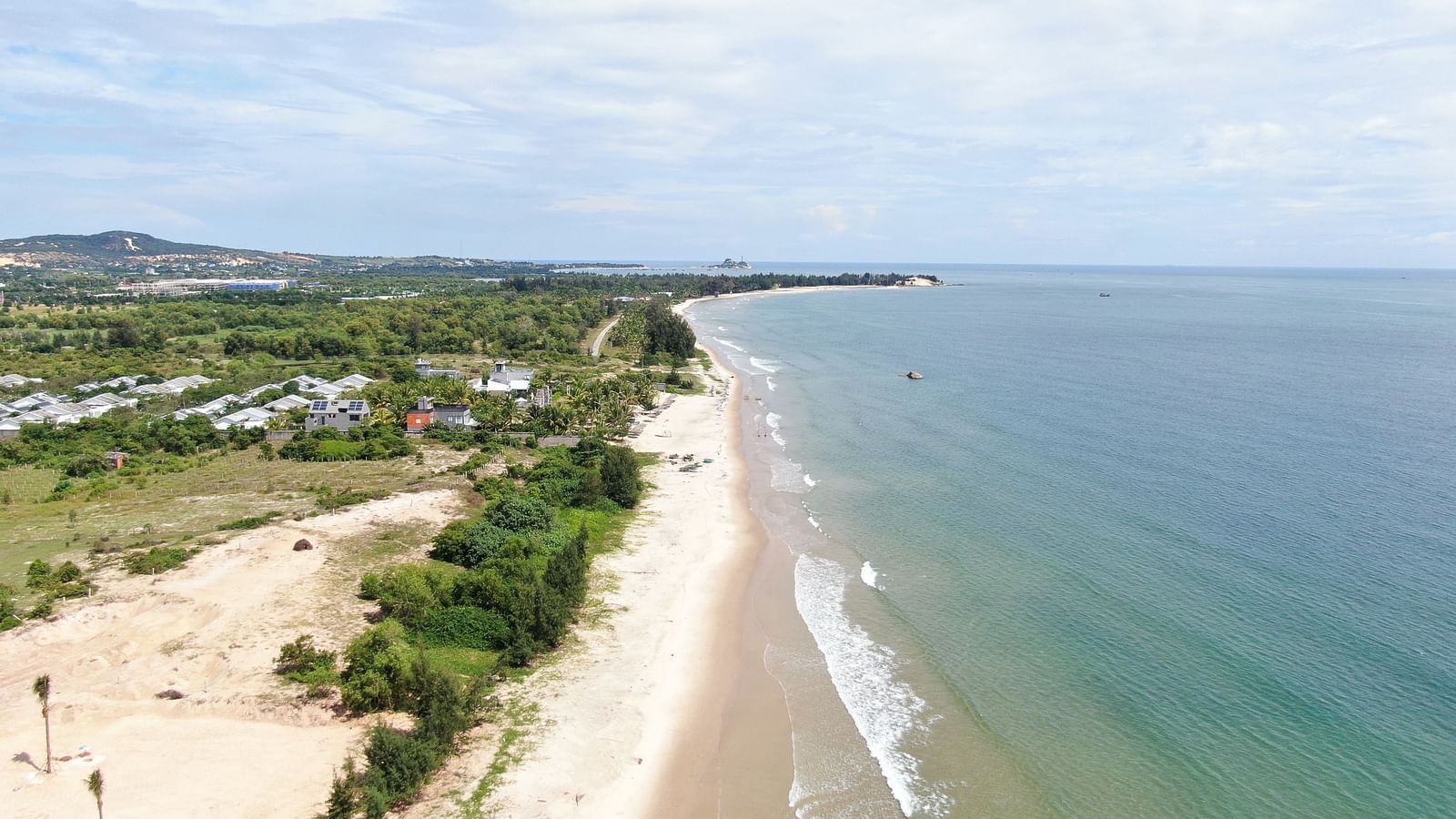An aerial view of a white beach on a sunny day with waves overlapping the beach - WoCAL Retreat Ke Ga