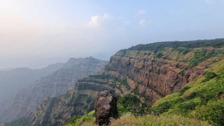 Stunning landscape of the Western Ghats with rugged cliffs and lush greenery under a clear sky.