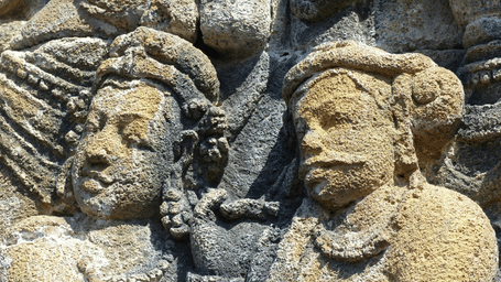 A stone carving depicting two figures with detailed headwear.