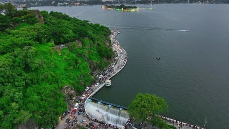 An aerial view of a solitary Fateh Sagar Lake Boat Ride with an island in the centre and greenery all around.