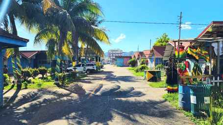 An overview of Montego Bay Craft Market with shops selling trinkets and coconut trees next to the road - Hotel 39, Jamaica.