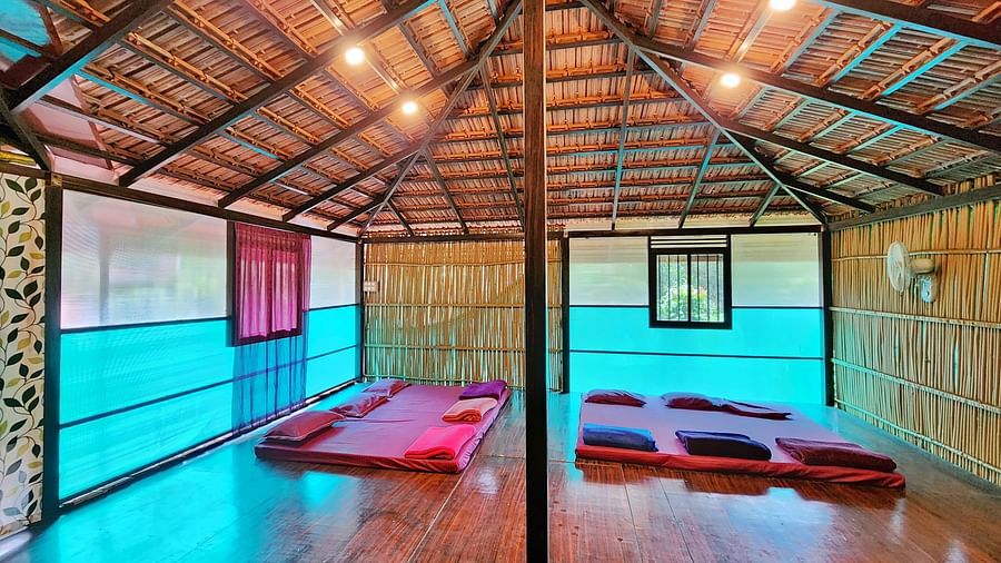 A room in the Group Wooden Cottage with comfortable red beds under a high wooden ceiling - Evergreen County