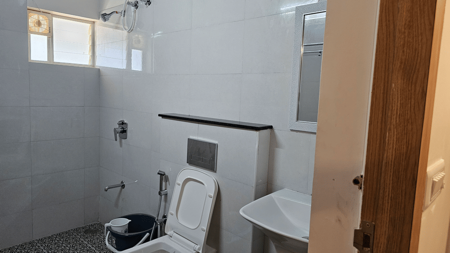 Attached bathroom with a shower area, western toilet, washbasin, and modern fittings.