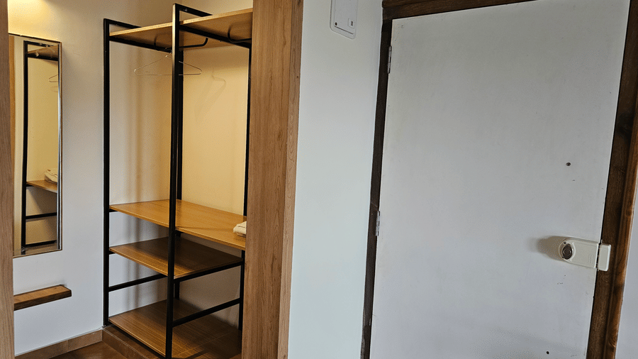 Guest room entrance with an open wardrobe, luggage rack, and dressing area.