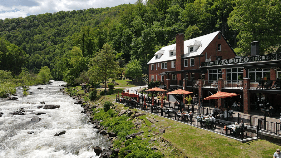 a beautiful facade image of our resort surrounded by lush greenery with a river stream flowing in front of it - Historic Tapoco Lodge