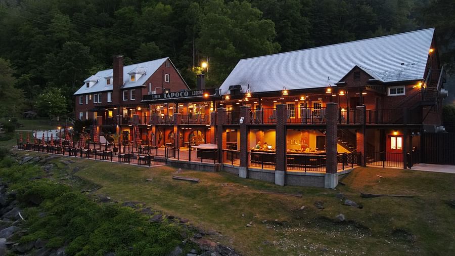 side view of our resort with bright yellow lighting with lush green pine forest in the background - Historic Tapoco Lodge