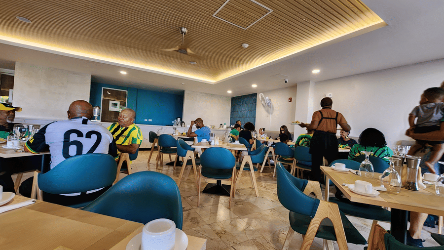 Dining area with vibrant blue chairs, warm overhead lighting, and set tables at one of the top restaurants in Montego Bay | Hotel 39, Jamaica