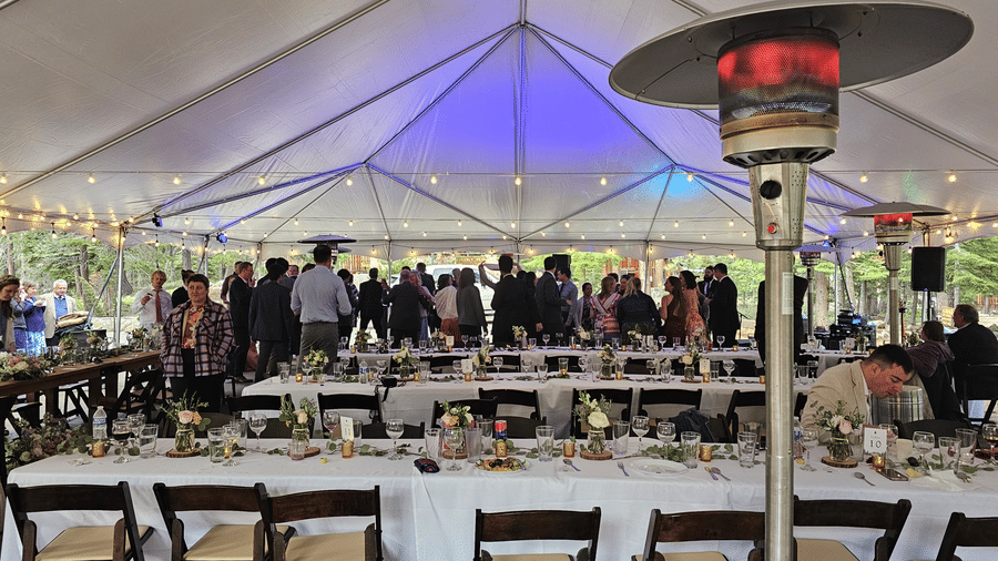 A festive outdoor dining setup at Kit Carson Lodge with heaters and string lights under a large event tent