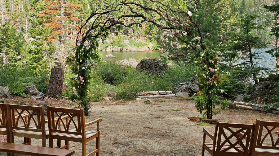 Rustic wooden arch overlooking the water, framed by benches and pine trees at our Silver Lake wedding venue | Kit Carson Lodge