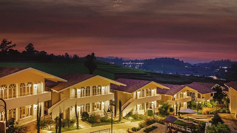 Aerial view of Mango Hill Shola, Ooty, with tiled-roof buildings arranged around a paved pathway and bordered by trees.