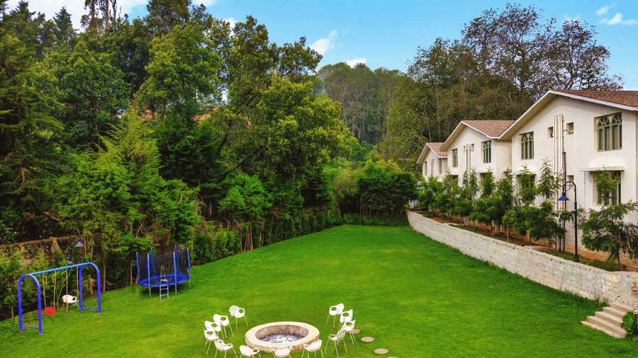 Central lawn at Mango Hill Shola, Ooty, featuring a circular stone arrangement, surrounded by resort buildings and natural vegetation.