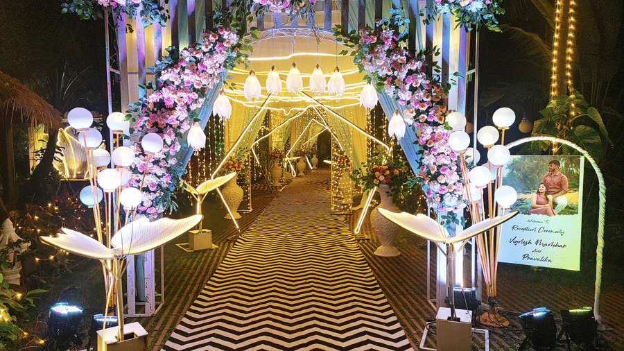 Entrance arch decorated with pink and white flowers and lights at Paradise Lagoon Resort, Udupi.