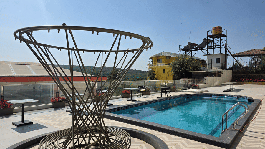 An outdoor swimming pool filled with water, surrounded by paving tiles at Savyasaachii Hotel.