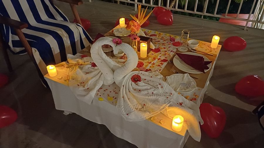 An elegantly decorated outdoor table for two, featuring swan-shaped towel art, candles, and red balloons. - Sea Hills Resort, Swaraj Dweep (Havelock)