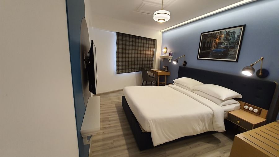 Shot of a  hotel room with a bed, a desk, and a large window with a view  | T24 Retro