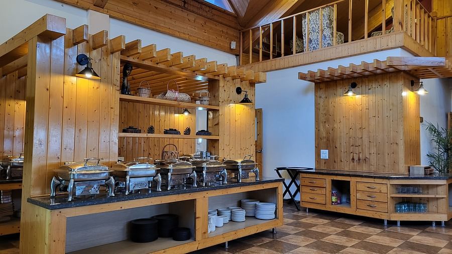 Buffet setup in a wooden-themed dining hall with high ceilings at Dagshai Manor Kasauli - Inde Hotels.