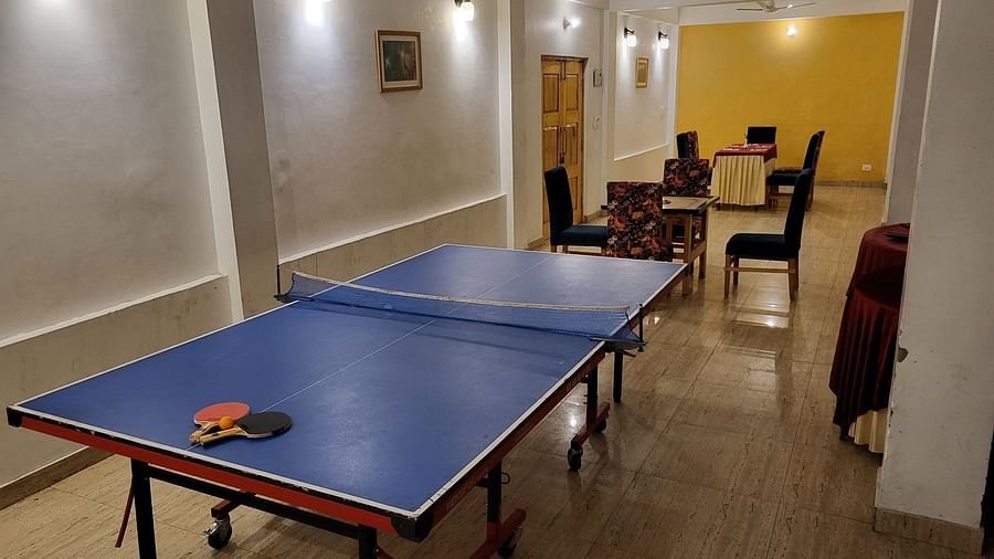 An indoor recreational area featuring a blue table tennis setup in a spacious corridor at Dagshai Manor Kasauli - Inde Hotels.