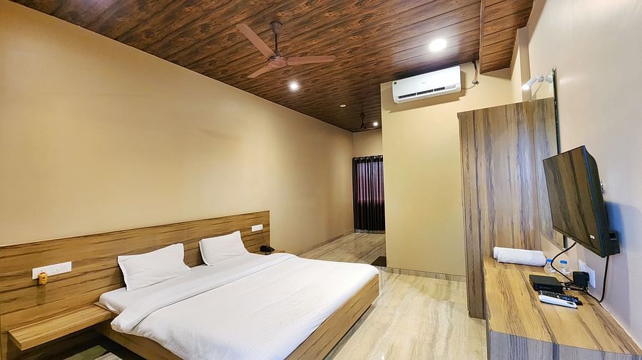 Pool View Standard Room at The Kanila Resort with a queen sized bed, a nightstand, a TV, and a desk. 