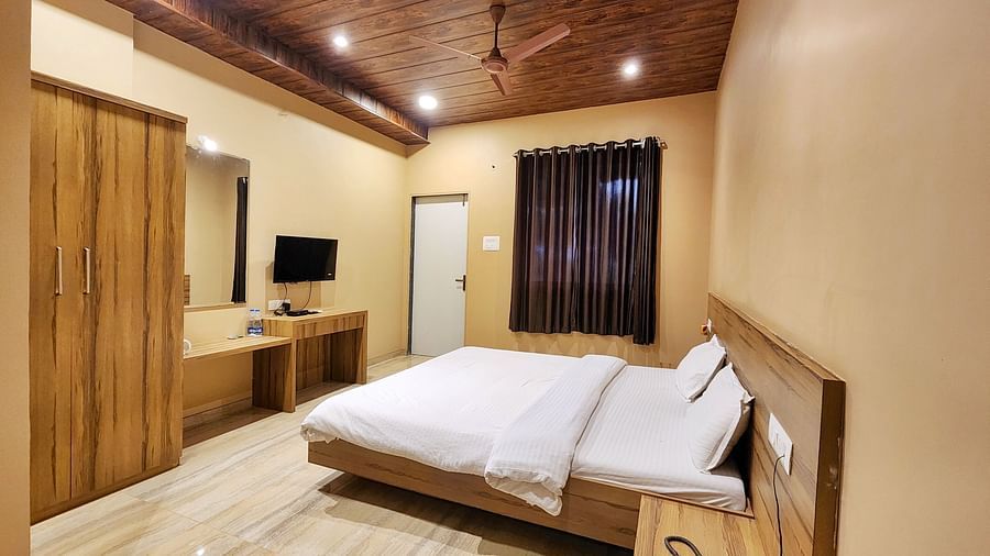 Overview of a Pool View Standard Room at The Kanila Resort with a queen sized bed, a nightstand, a TV, and a desk. 