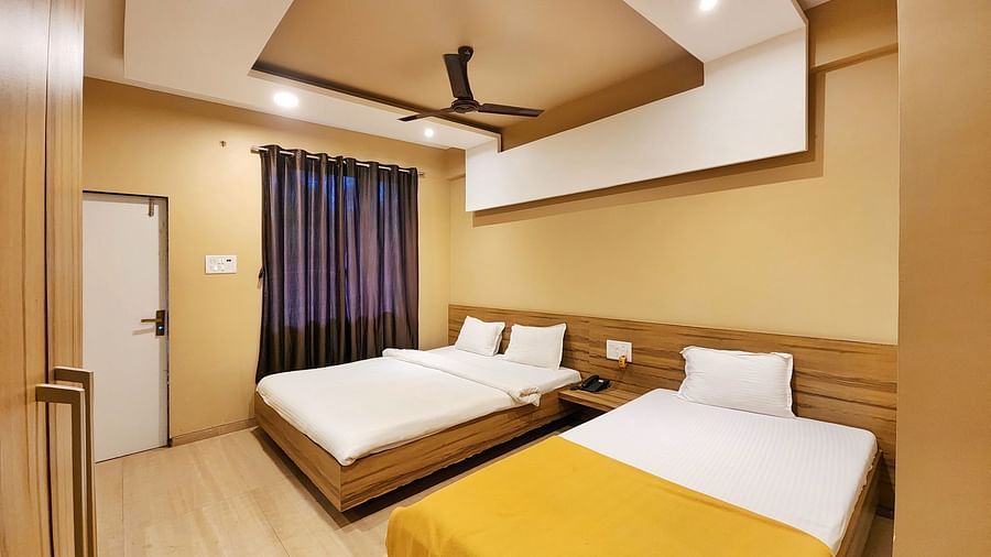 Overview of Triple Premium Room at The Kanila Resort featuring a bed with a gray headboard and white sheets and a window.