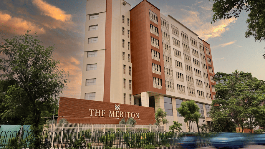 The exterior of The Meriton, our hotel in New Delhi, seen during the early evening with a road in front of it featuring a beautiful evening sky in the background.