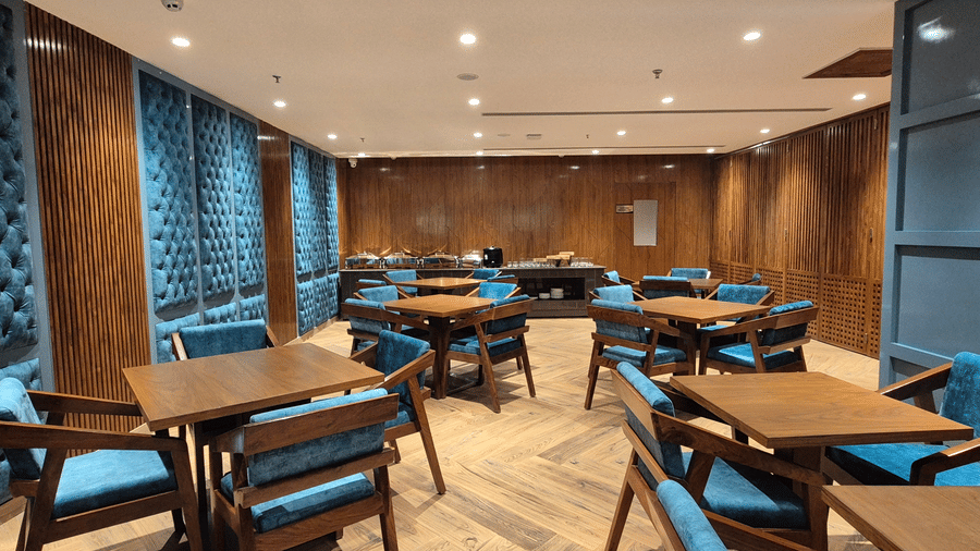 Compact dining space with wooden tables, teal chairs, and soft lighting