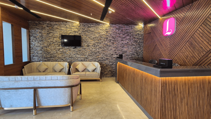 Hotel Reception with stone accent wall, wooden desk, ceiling lights, and beige sofas.