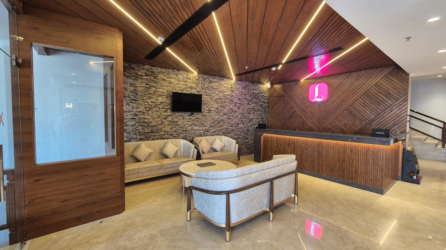 Reception area with L-shaped wooden desk and contemporary ceiling design.