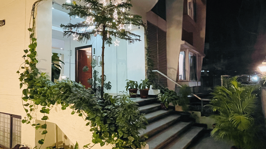 Hotel entrance pathway with lush potted plants and warm lighting at Sanctum Suites Indiranagar, Bangalore.