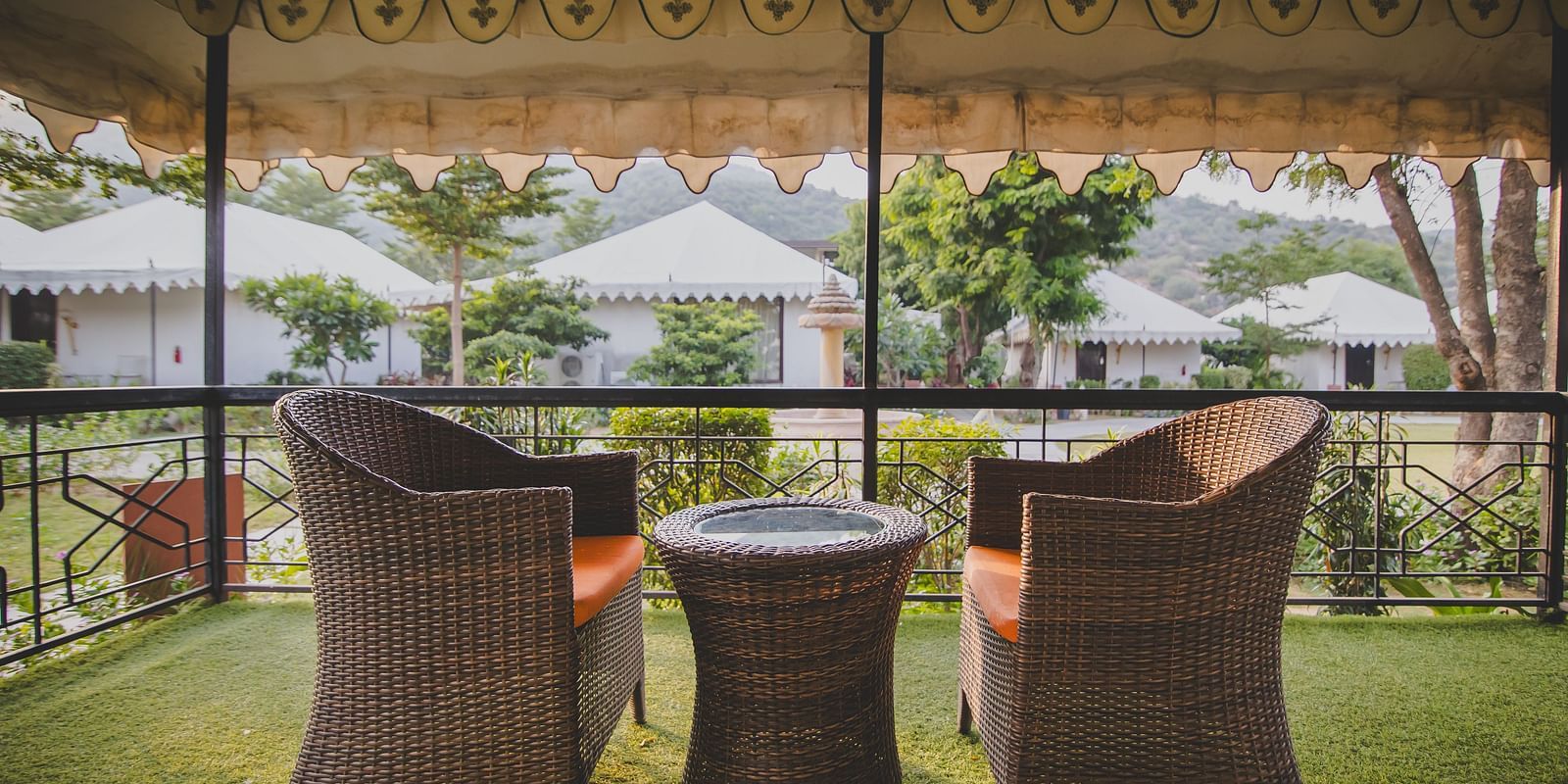 Image of a balcony with a two chairs and a table in between at Rajasthali Resort & Spa Jaipur.