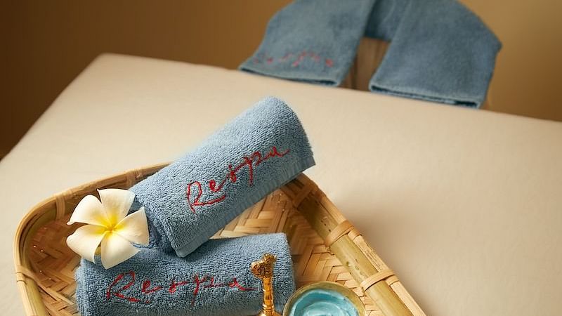 A tray with folded towels and decorative items on a white surface.