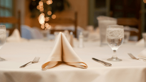 An elegantly set dining table with a folded napkin and glasses, ready for a meal