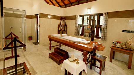 Spa room with massage beds and wooden decor at Vythiri Resort, Wayanad