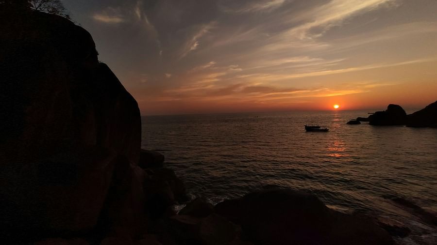 An overview of butterfly beach in goa with a solitary boat on the water and sun setting in the background