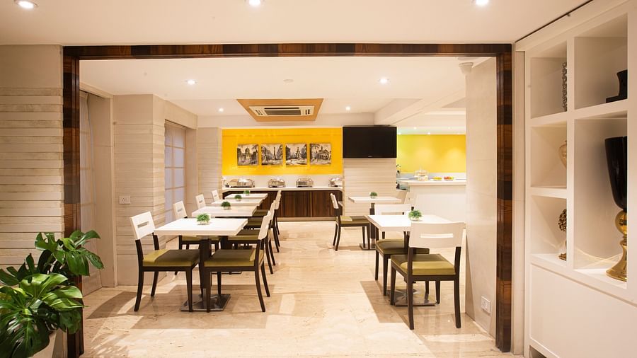 A wide-angle view of a dining area featuring a flat-screen TV on the wall, with neatly arranged tables and chairs, creating an inviting atmosphere.