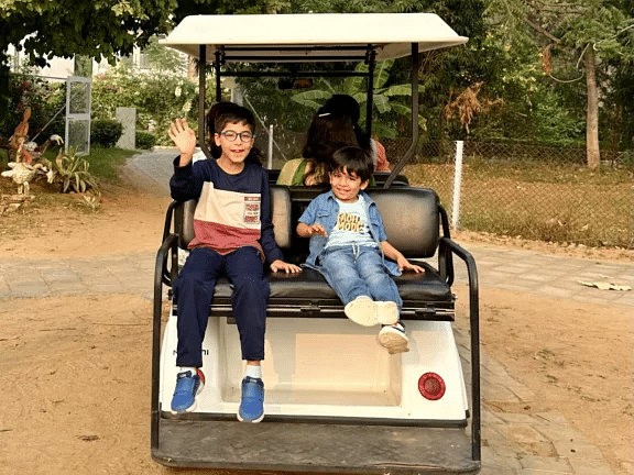 Guests being transported in a white golf cart along a tree-lined path at Karma Chalets.