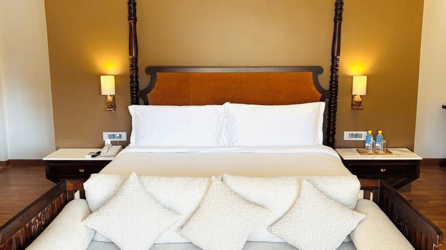 Vana Suite at Surpura Bagh featuring double side bed, bedside table and lamp on either side, and a sofa attached to the bed. 