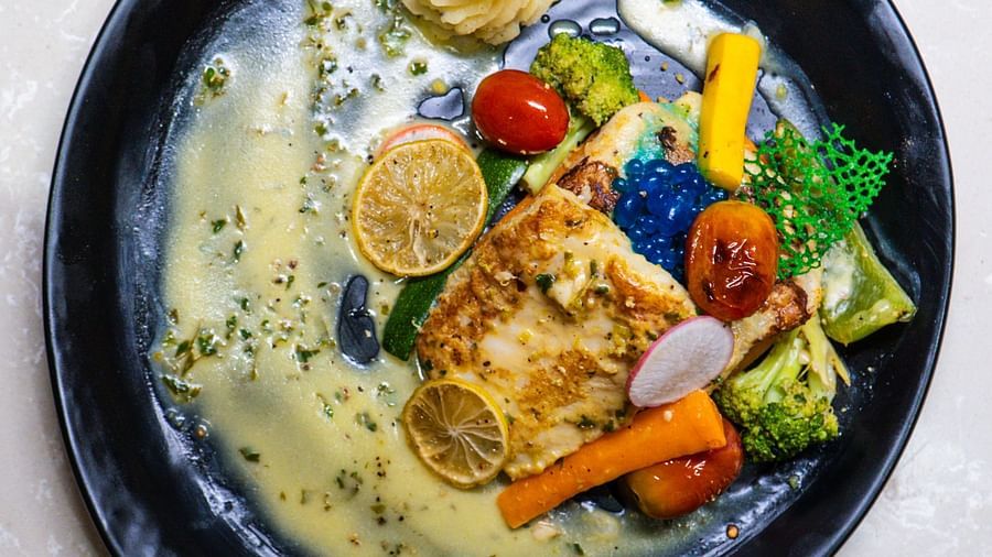 Fish with vegetables on a plate with sauce, with a focus on the textured fish and greens.