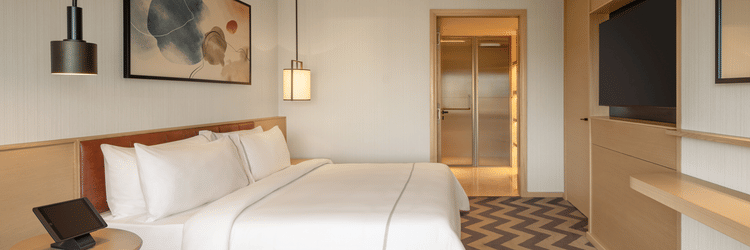 Side view of a luxurious suite room featuring a cozy bed and elegant bedside lamps at The Residency Chennai