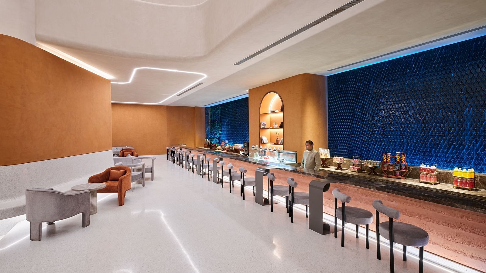 Image of Bean Hive restaurant with chairs arranged next to a running table and a bartender standing on the other side of the table