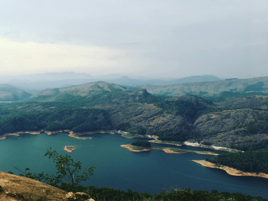Panoramic landscape view of the dam reservoir and distant mountains from a viewpoint.
