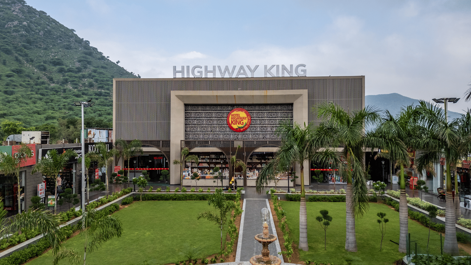 Grand exterior facade and manicured lawn leading up to the hotel entrance at Hotel Highway King, Neelka.